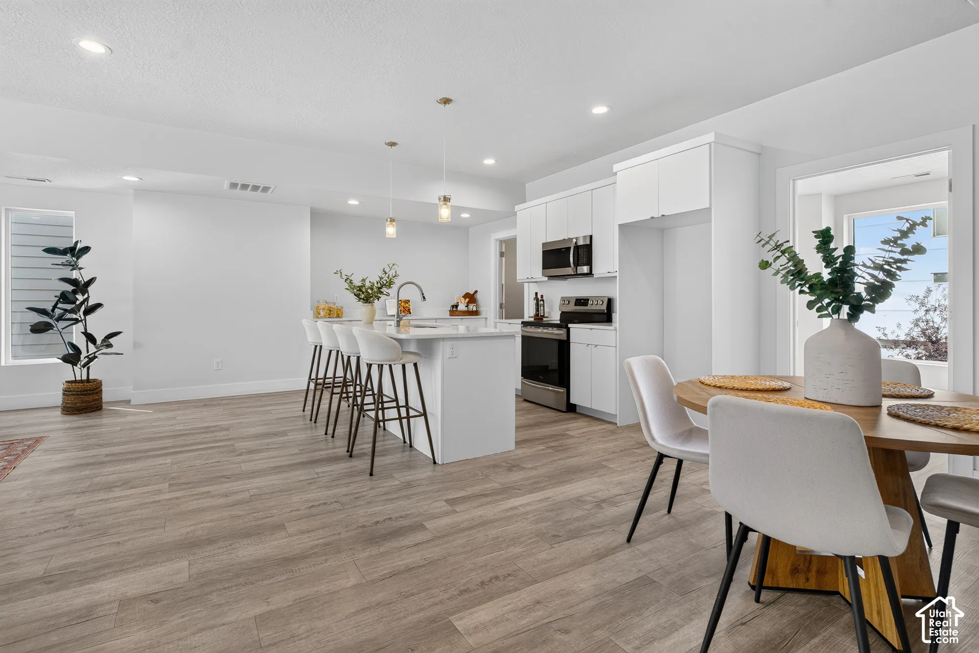 Open-concept living space with wood-finish flooring, recessed lighting, and a kitchen island with pendant lighting