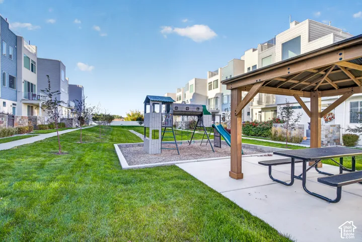 Community green space featuring a wood gazebo with a picnic table, a playground with a slide, and a manicured lawn