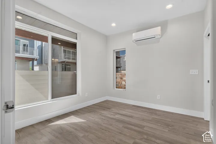 Wood-finish flooring, recessed lighting, and a wall-mounted climate control unit