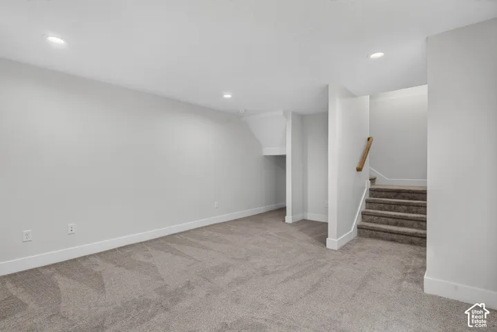 Recessed lighting, light gray carpeting, white walls, white baseboards, and a wooden handrail