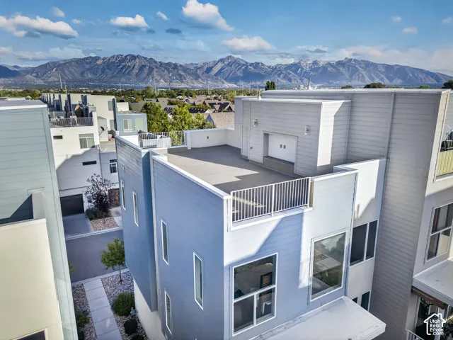 Multi-level modern exterior with a rooftop patio, contemporary siding, large windows, and a mountain backdrop