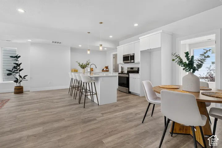 Open-concept living space with wood-finish flooring, recessed lighting, and a kitchen island with pendant lighting