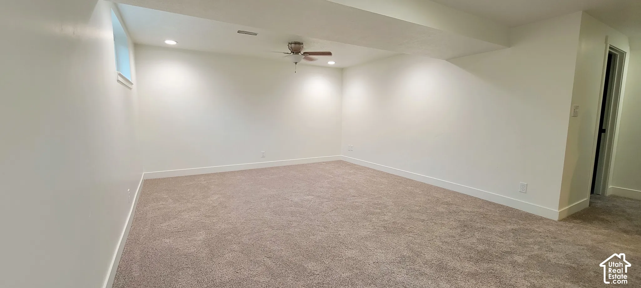 Recessed lighting illuminates this room with neutral-toned carpeting and a ceiling fan