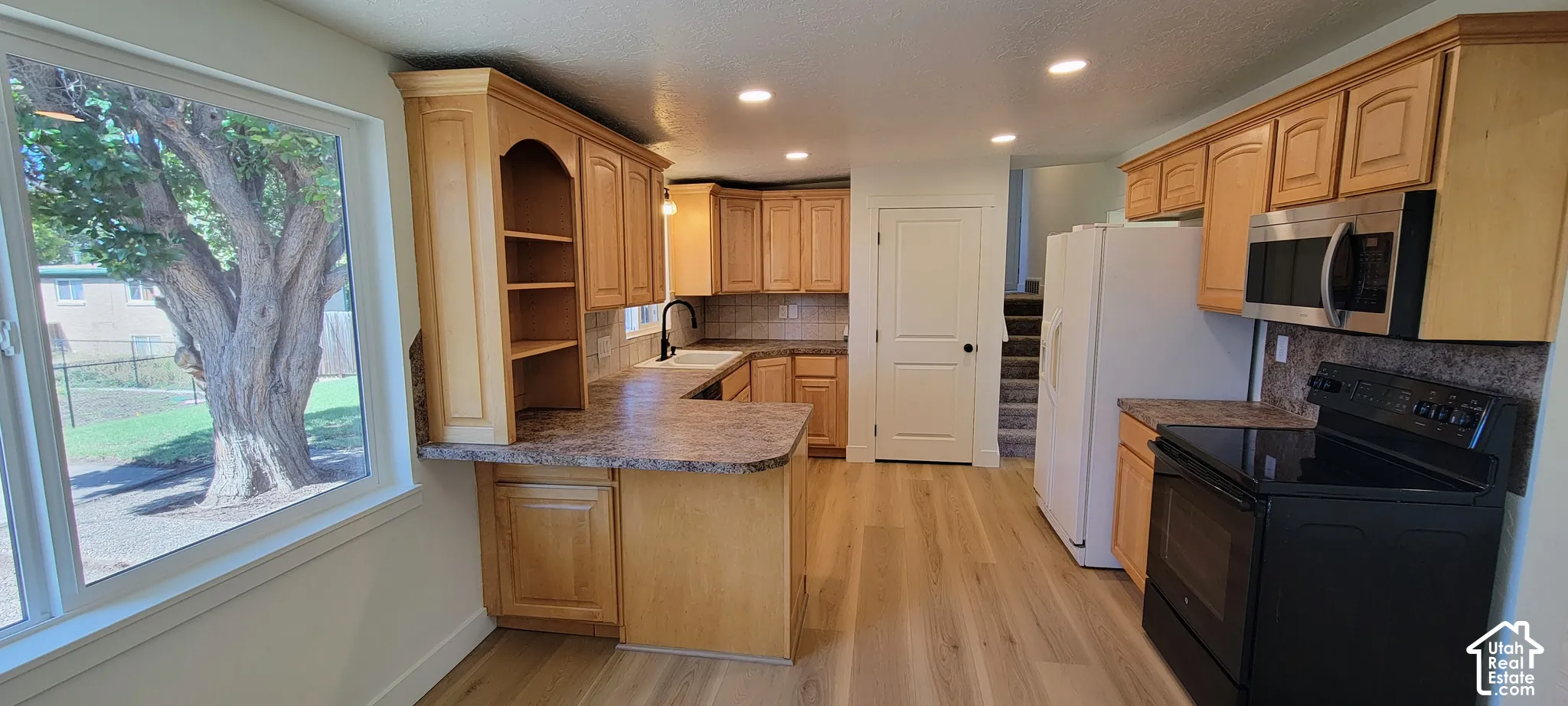 Kitchen featuring wood-finish flooring, recessed lighting, wood cabinetry, and a built-in microwave