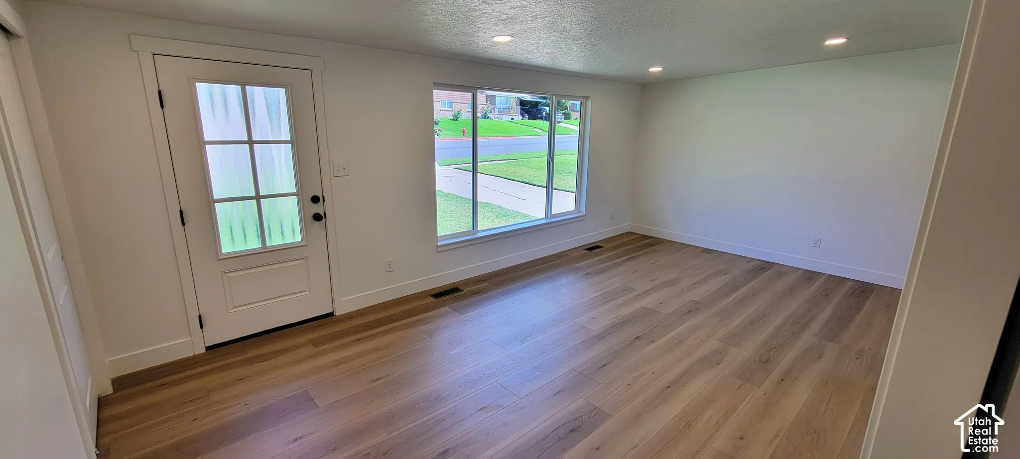 Light wood-finish flooring, recessed lighting, and a white paneled door with windowpane detailing