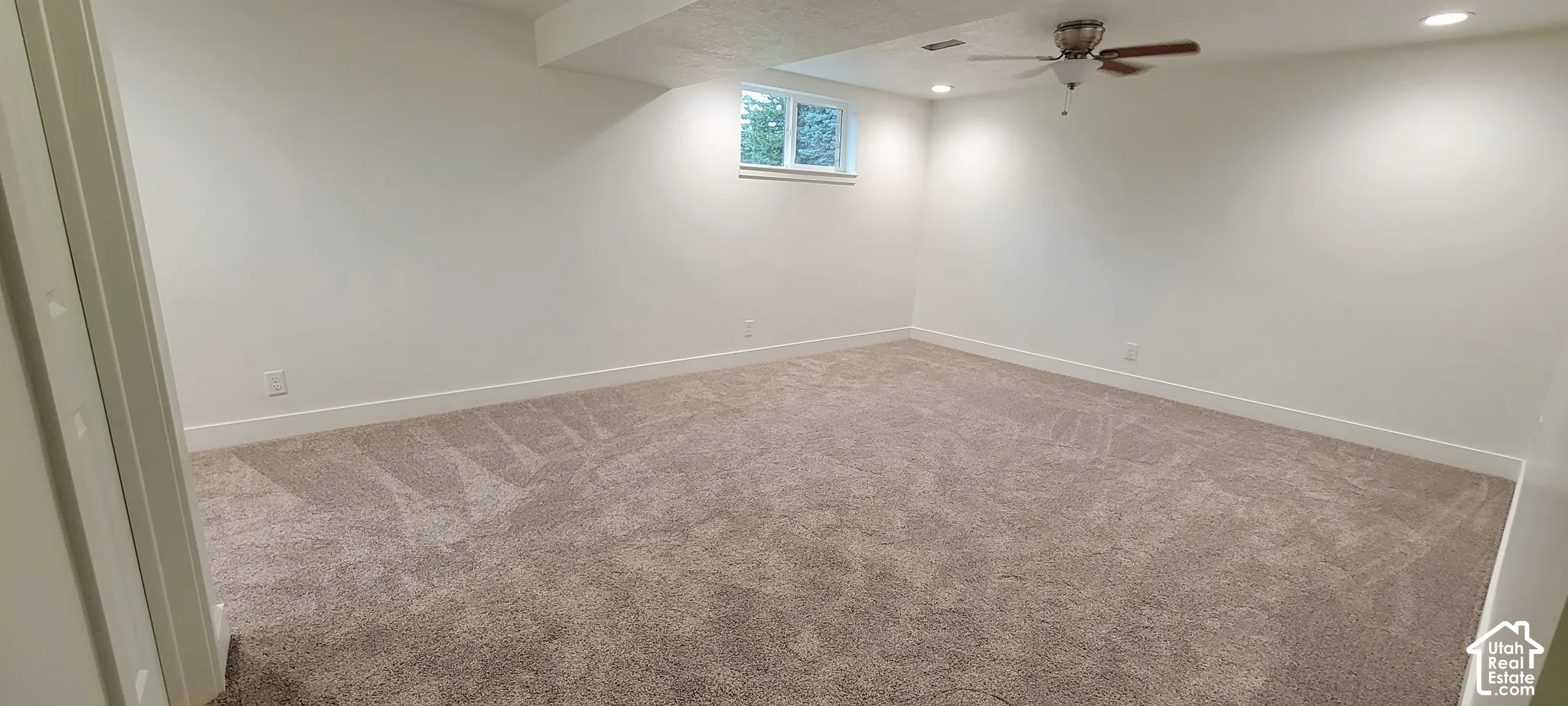 Spacious room featuring neutral carpeting and white painted walls