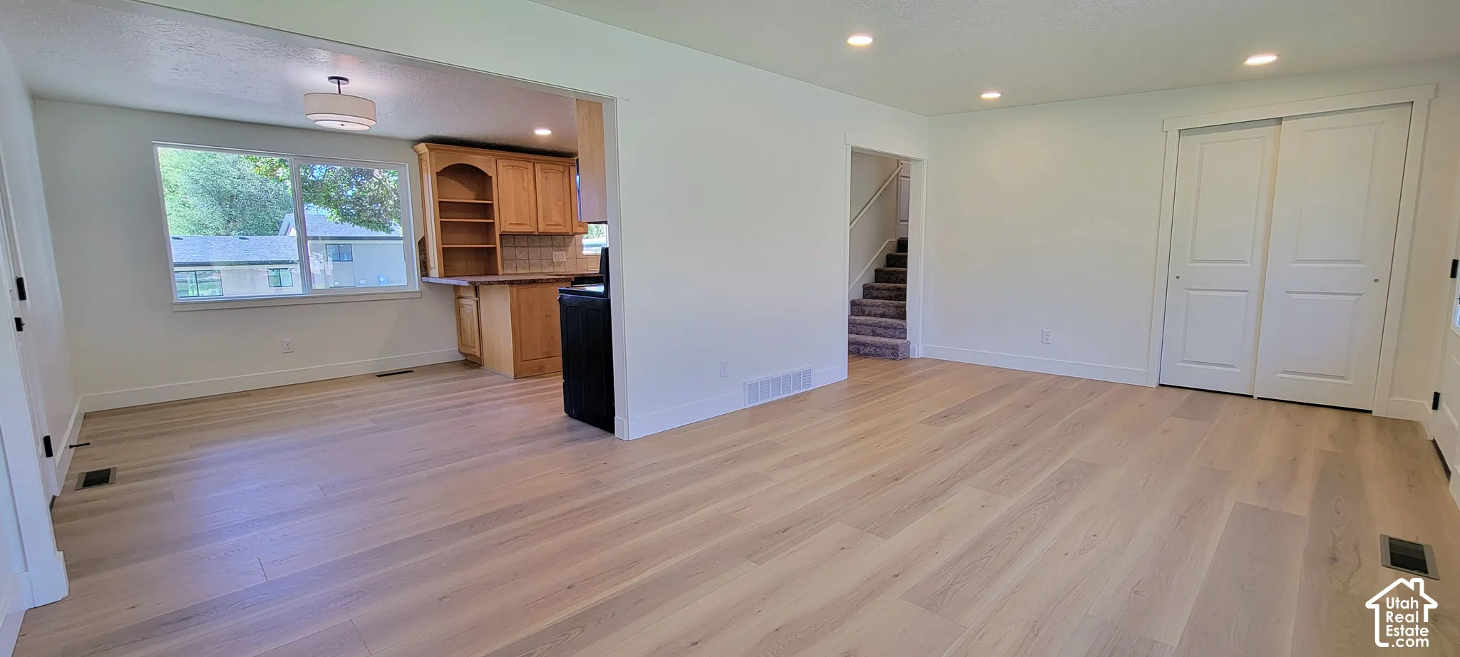 Open-concept living area featuring light wood-finish flooring, recessed lighting, and white walls