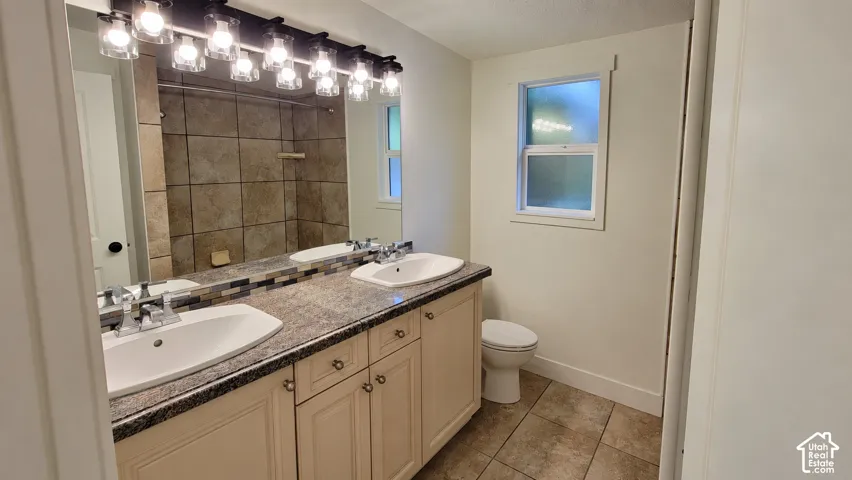 Dual vanity with undermount sinks, stone-finish countertop, and decorative backsplash
