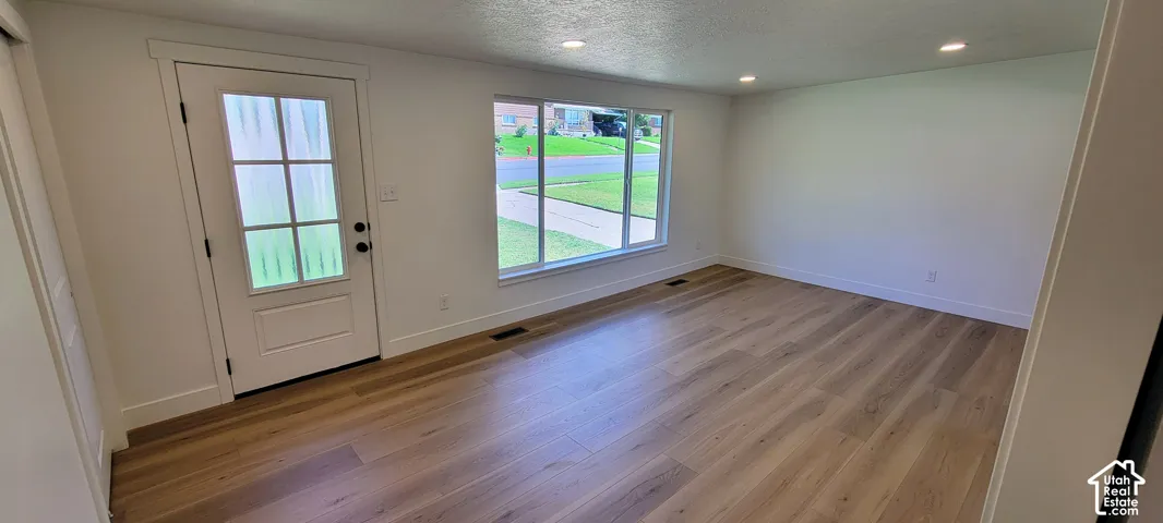 Light wood-finish flooring, recessed lighting, and a white paneled door with windowpane detailing