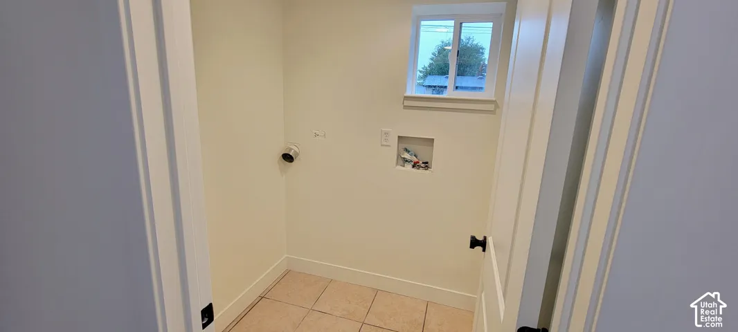 Dedicated laundry area featuring ceramic tile flooring, a single window, and a white trim package