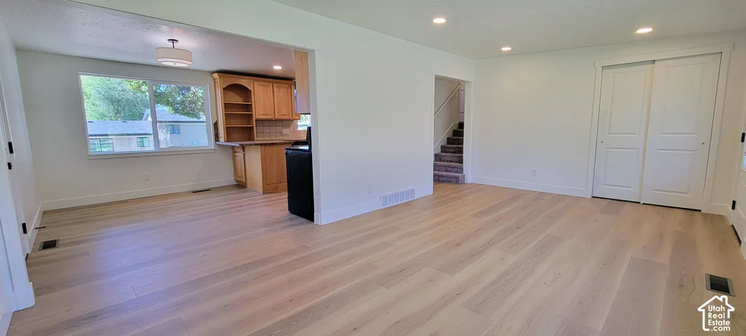 Open-concept living area featuring light wood-finish flooring, recessed lighting, and white walls