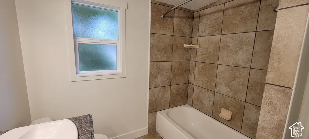 White bathtub with tiled surround and chrome shower rod