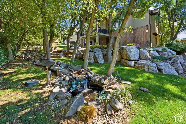 Terraced landscaping featuring a rock retaining wall, mature trees, a stream, and a cascading waterfall feature
