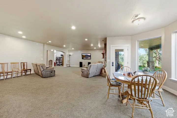 Expansive carpeted room with recessed lighting and natural light from large windows