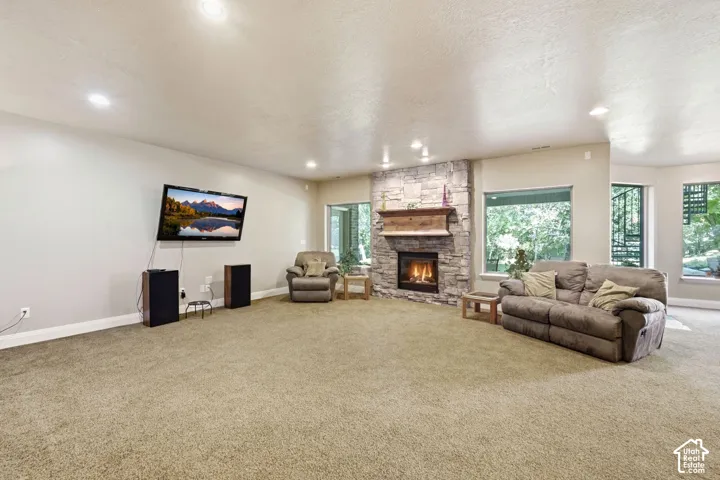 Recreational room featuring a stone-clad fireplace with a wood mantel, recessed lighting, and expansive windows