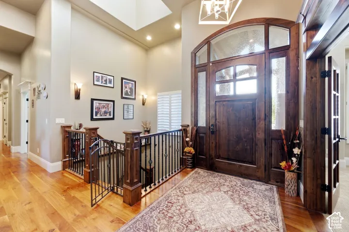 Grand entryway featuring a wood-finish front door with an arched transom, wood-finish flooring, a wrought iron and wood-finish staircase, and wall sconces