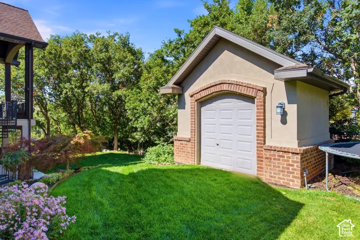 Detached garage with brick and stucco exterior, arched brick detailing, and a paneled overhead door