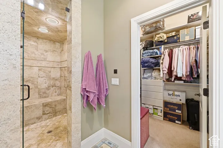 Glass-enclosed shower with stone tile, recessed lighting, and a built-in bench