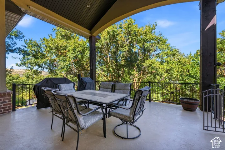 Expansive covered patio featuring a concrete surface, decorative metal railings, and a brick column accent