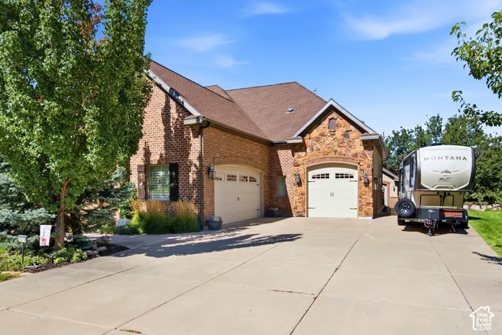 Brick and stone exterior with a multi-car driveway, attached two-car garage, and an additional single-car garage