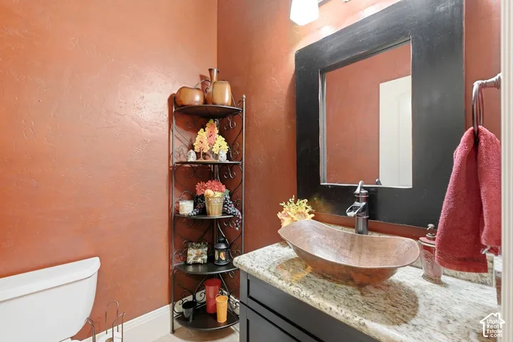 Textured wall finish, built-in corner shelving, vessel sink, granite countertop, and framed mirror