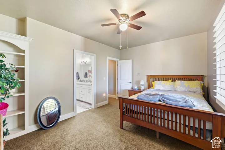 Built-in shelving unit, ceiling fan with integrated lighting, window with horizontal blinds, and carpeted flooring