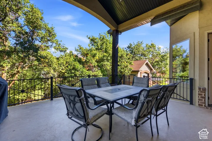 Covered outdoor patio with a concrete surface, black iron railing, and a dark wood ceiling