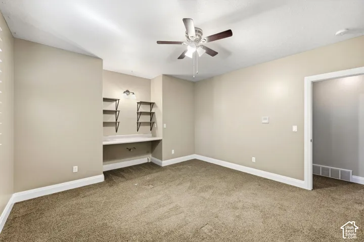 Built-in desk with a light-toned countertop, integrated shelving, and wall-mounted lighting