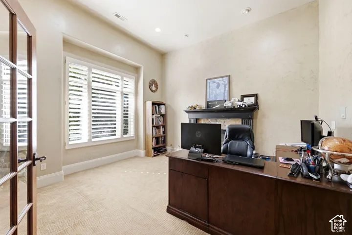 Recessed lighting illuminates a carpeted interior featuring a fireplace with a dark mantel