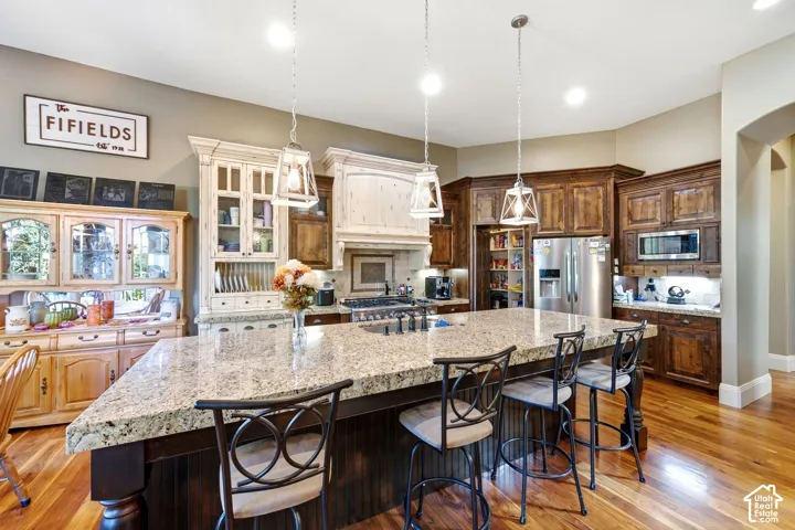 Hardwood flooring, light wood-finish cabinetry, dark wood-finish cabinetry, stainless steel appliances, and a large central island with seating
