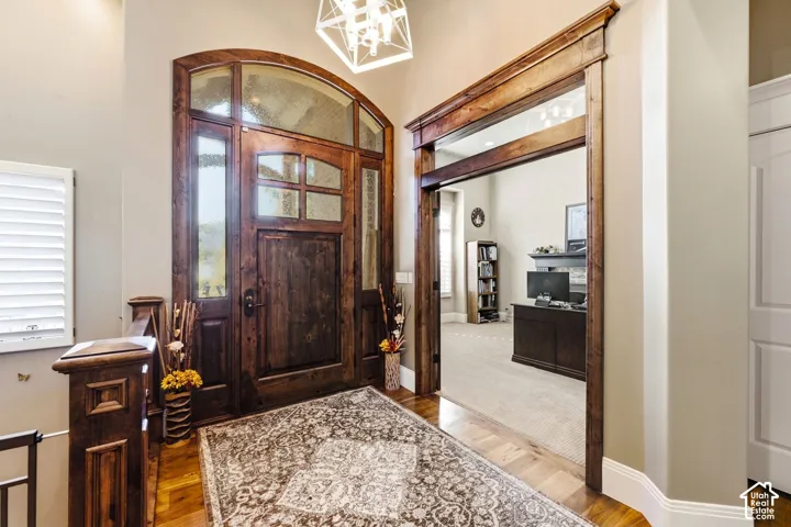 Arched wooden entry door with frosted glass panels, wood-finish flooring, and a decorative overhead light fixture