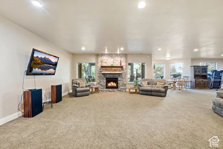 Stone-surround fireplace with a wood mantle, recessed lighting, and multiple windows