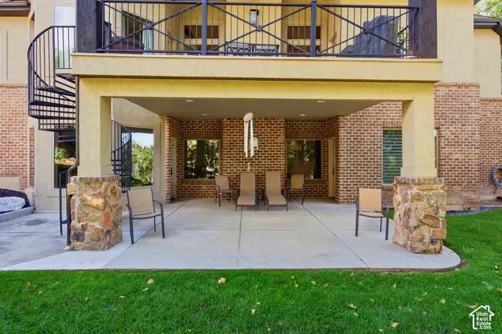 Covered patio featuring a concrete surface, stone-clad pillars, and brick wall accents