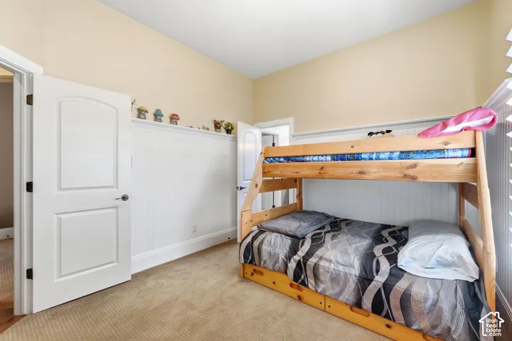 Plush carpet flooring, beadboard wainscoting, and a window with horizontal blinds