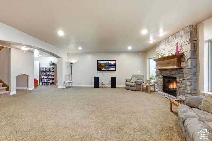 Expansive room featuring a stacked stone fireplace with a wood mantel, recessed lighting, and carpet flooring