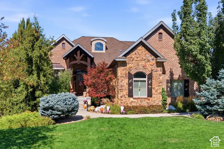 Brick and stone facade with an arched entry, decorative window shutters, and a dormer window