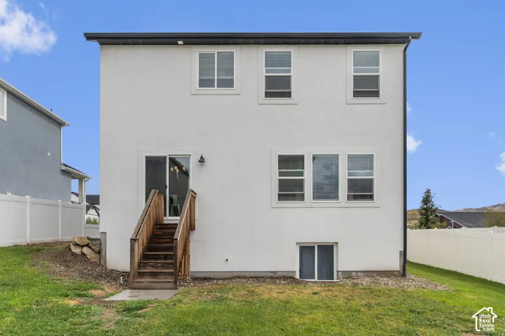 White stucco exterior with multiple windows, second-story sliding glass door, and wooden stairs
