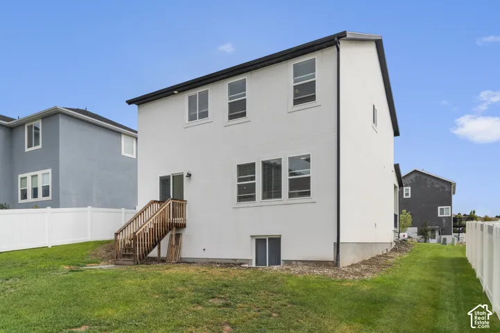 Rear exterior featuring white stucco siding, a walk-out basement, and a wooden deck with stairs to the yard
