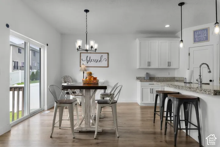 Wood-finish flooring throughout, white cabinetry with dark hardware, stone countertops, and a sliding glass door