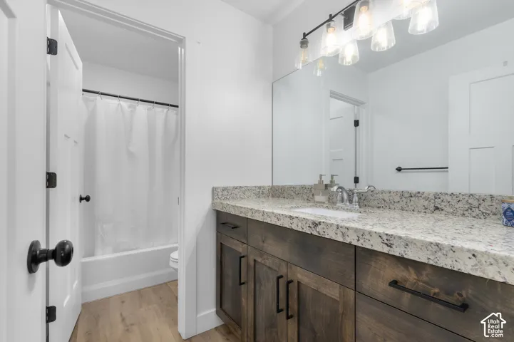 Wood-finish flooring with a white bathtub and shower rod