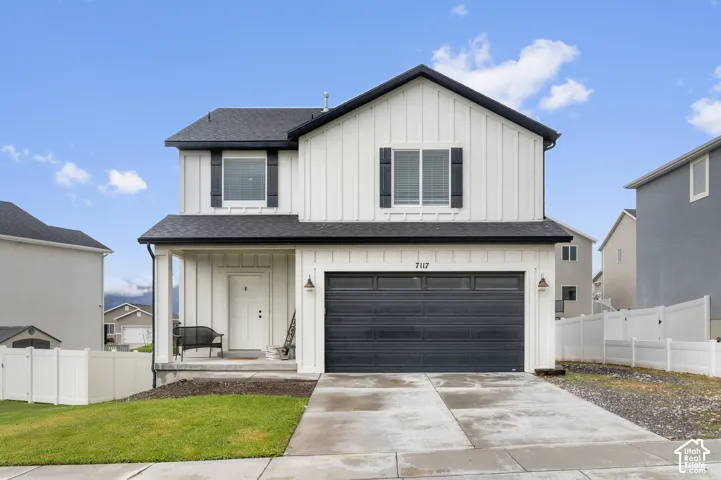 Two-story exterior with board and batten siding, dark shingle roof, two-car garage, and concrete driveway