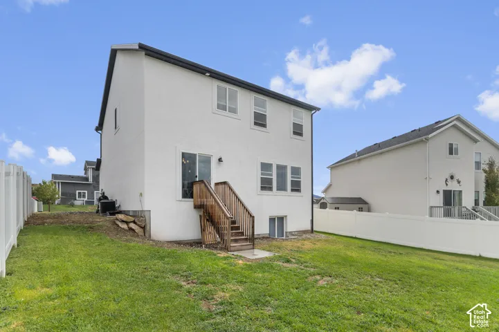 Expansive lawn space with a privacy fence, wood staircase, and sliding glass door