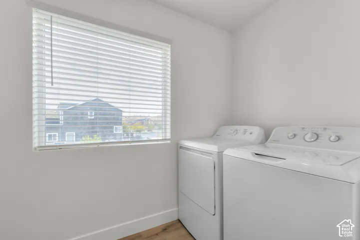 Wood-finish flooring with white walls and a window featuring horizontal blinds