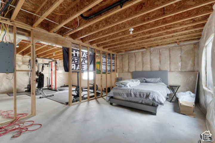 Unfinished lower level featuring exposed wood framing, concrete flooring, and insulated walls