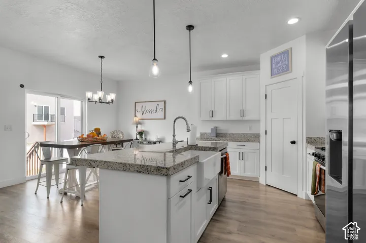 Kitchen with granite countertops, white cabinetry, stainless steel appliances, and wood-finish flooring