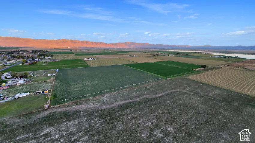 Expansive agricultural land with varied cultivated fields, offering a distant mountainous backdrop and a body of water