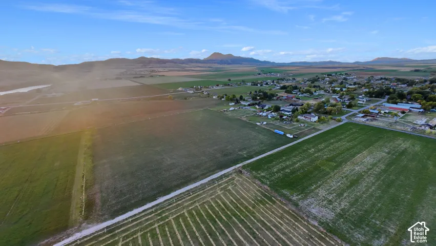 Expansive rural landscape featuring cultivated fields and distant residential structures