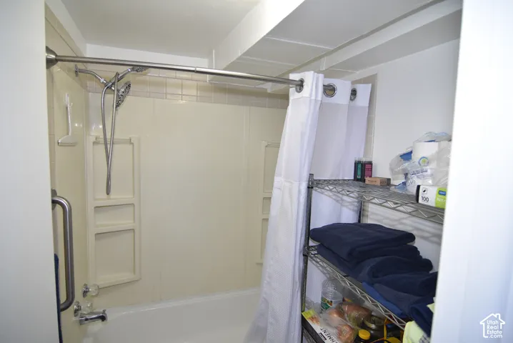 ADU Private tub/shower comb with grab bar, featuring a shower surround with integrated shelving
