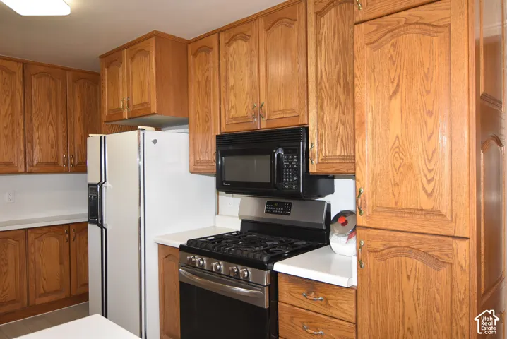 Extensive wood cabinetry, white countertops, built-in microwave, and stainless steel gas range