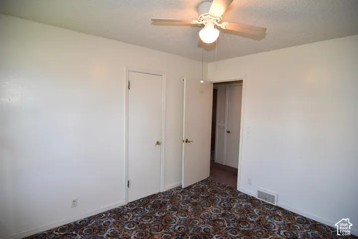 Bedroom #1 Ceiling fan with integrated lighting, textured ceiling, patterned carpet flooring, white walls, and white interior doors